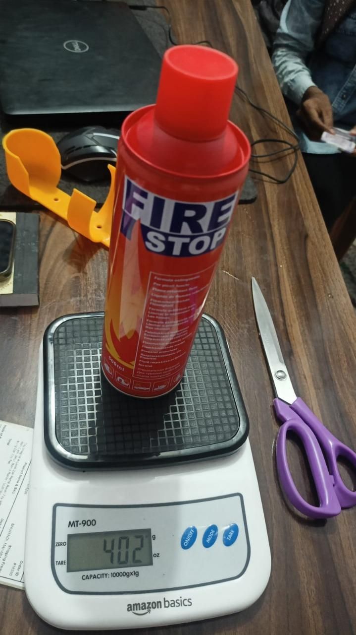 Fire extinguisher on a digital scale with scissors and a box in the background