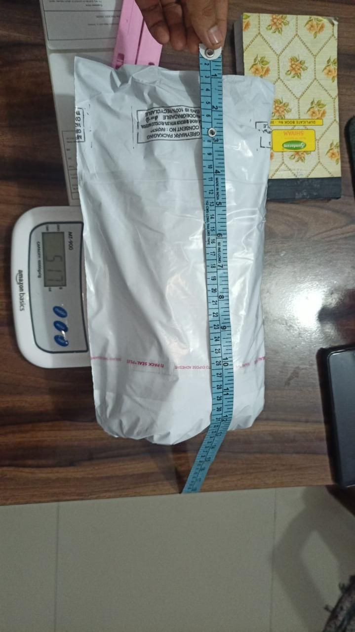 White package being measured with a ruler on a wooden surface