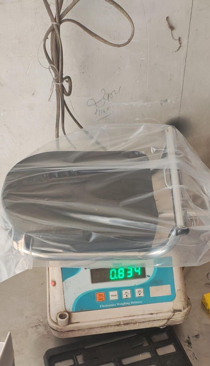 Digital scale with a transparent plastic cover on a concrete floor.